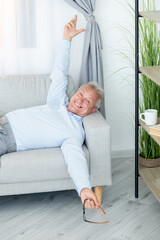 Happy senior man. Couch relaxing. Vacation holiday. People leisure. Joyful mature male employee having work break resting on sofa at home living room.