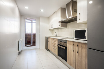 Kitchen with light wood furniture, gray appliances and glass door with white aluminum frame