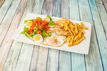 Healthy combo plate with french fries, grilled chicken fillet and one fried and one sliced egg cooked with salad and carrot