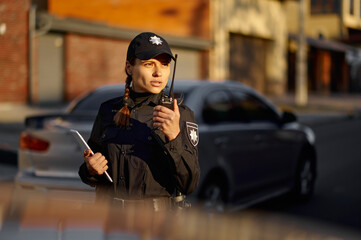 Police woman talking using walkie-talkie during patrolling