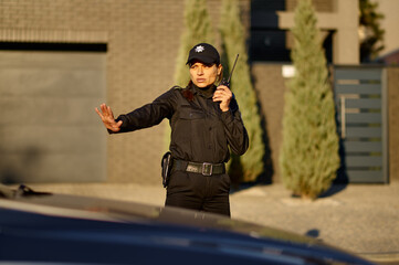 Police woman using walkie-talkie controlling road traffic