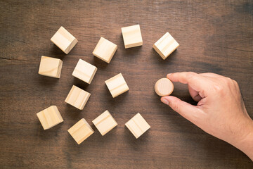 Hand put a different shape of wood blocks among the similar wood cubes on the table, concept for...