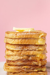 eggy bread on a pink background. Butter melts on a stack of eggy breads. Tasty breakfast.