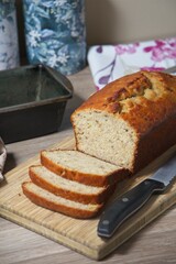 Freshly baked banana bread, sliced. on a wooden board with knife