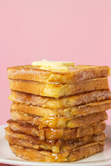 eggy bread on a pink background. Butter melts on a stack of eggy breads. Tasty breakfast.