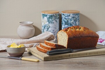 Freshly baked banana bread, sliced. on a wooden board with knife