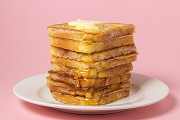 eggy bread on a pink background. Butter melts on a stack of eggy breads. Tasty breakfast.