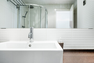 Close-up of white porcelain sink with white tile and recessed mirror