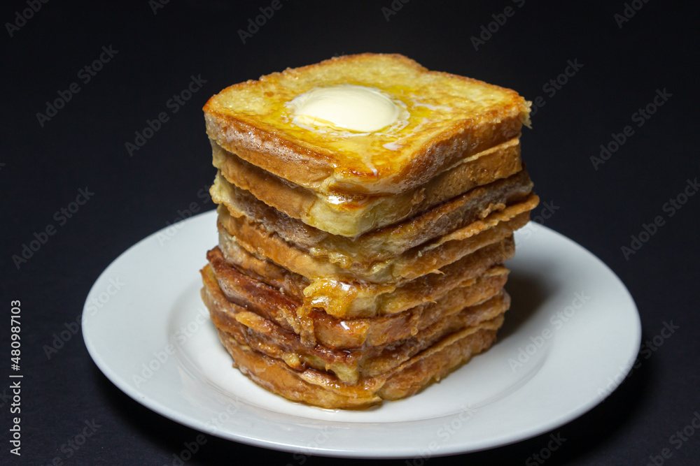 Wall mural eggy bread on a black background. Butter melts on a stack of eggy breads. Tasty breakfast.