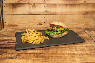 Beef burger with tomatoes and pumpkin seeds, melted cheese and lamb's lettuce garnished with french fries