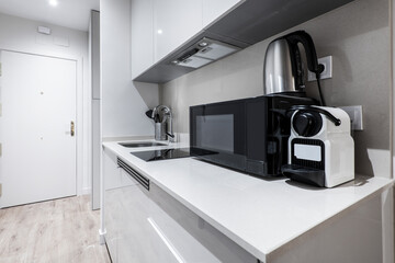 Fototapeta na wymiar small kitchen of a gray apartment with microwave, water fort and coffee capsule machine