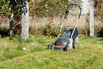 Lawn mowing, lawn mower on green grass, garden care tool, close-up view, sunny day.