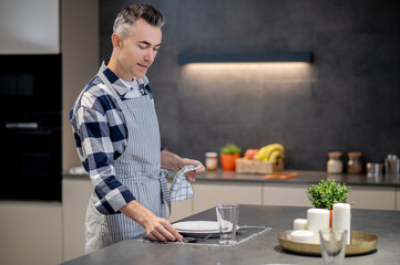 Man in apron wiping dishes and serving table