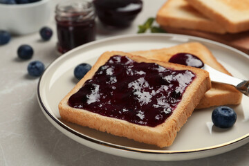 Toast with blueberry jam served on table, closeup