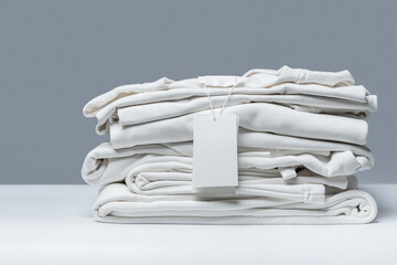 Stack of new white clothes with a blank garment tag