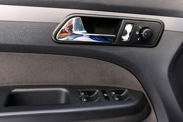 Inside the drivers door of a car with a window lifter. Car door handle. Automatic adjustment of mirrors.