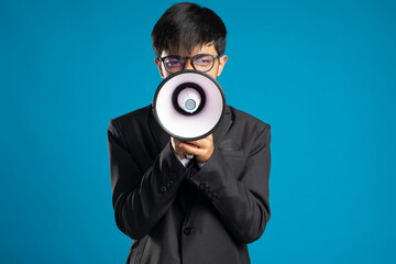 Young Business man screaming with a megaphone on blue background