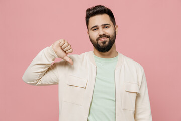 Young disappointed displeased dissatisfied man 20s wear trendy jacket shirt showing thumb down...