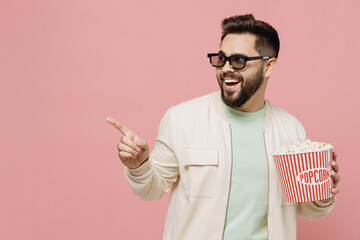 Young man in 3d glasses jacket shirt watch movie film hold bucket of popcorn point finger aside on...