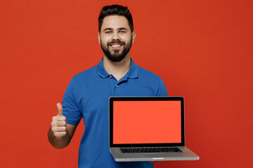 Young smiling happy satisfied man 20s wear basic blue t-shirt hold use work on laptop pc computer...