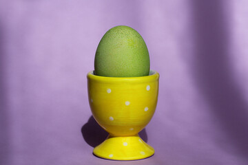 a bright green Easter egg in a special stand on a purple background. Easter decor.