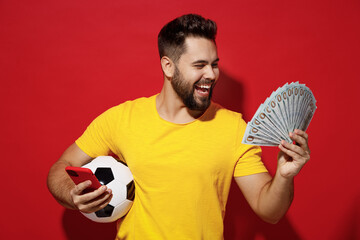 Fun young bearded man football fan in yellow t-shirt cheer up support favorite team hold soccer...