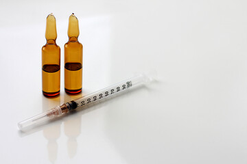 A syringe and glass ampoules with a medicine or chemical reagent on the table. The concept of a...