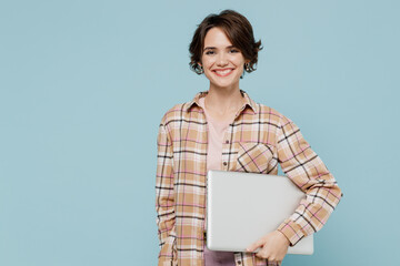 Young smiling happy satisfied woman 20s wearing casual brown shirt hold use work on laptop pc...