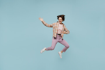 Full body young excited expressive musician happy woman 20s in casual brown shirt jump high play guitar isolated on pastel plain light blue color background studio portrait. People lifestyle concept.