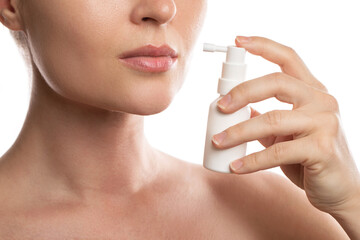 Woman is using spray with analgesic for sore throat relief