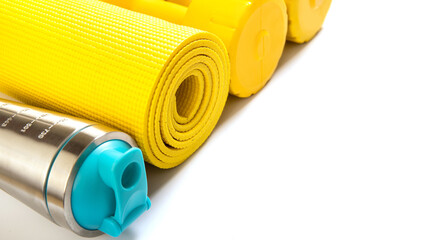 Yellow fitness mat and dumbbells on white background