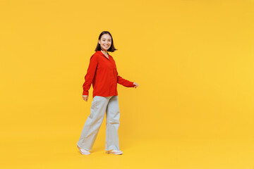Fototapeta na wymiar Full size body length vivid young woman of Asian ethnicity 20s years old in casual clothes look camera go move isolated on plain yellow background studio portrait. People emotions lifestyle concept.
