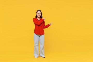 Full size body length vivid promoter young woman of Asian ethnicity 20s in casual clothes point fingers aside on workspace area copy space mock up isolated on plain yellow background studio portrait.