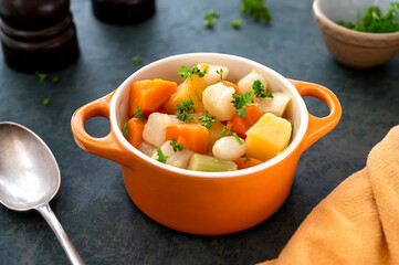 Roasted or baked root vegetables with fresh herbs, orange vegetables on plate. Vegan food.