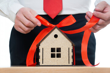 Salesman tying a red ribbon bow on a miniature house model