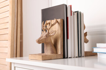 Wooden deer shaped bookends with books on table indoors