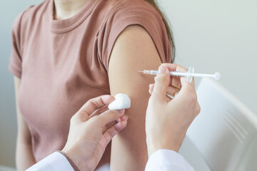 People getting a vaccination to prevent pandemic concept. Woman in medical face mask  receiving a dose of immunization coronavirus vaccine from a nurse at the medical center hospital