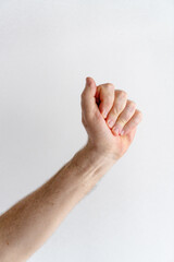 hand of an unrecognizable older man making a fist against the backdrop of a white wall, vertical photo