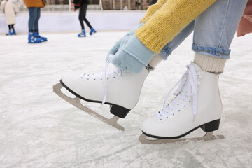 Woman lacing figure skates on ice rink, closeup