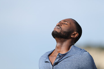 Relaxed man with black skin breathing fresh air outside