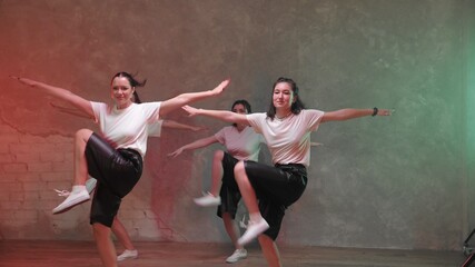 A group of beautiful girls dancing in a room with red and green lighting and. Dances