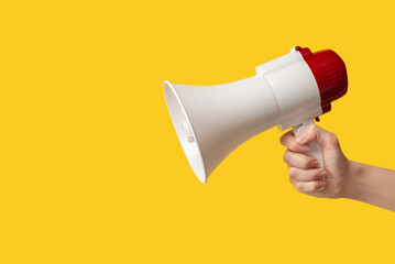 Megaphone in woman hands on a yellow background.