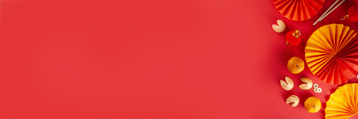 Chinese new year background. Red and golden yellow flatlay with traditional Chinese new year decor, envelopes with wishes, gold coins, fans, Chinese lanterns, oranges and tea