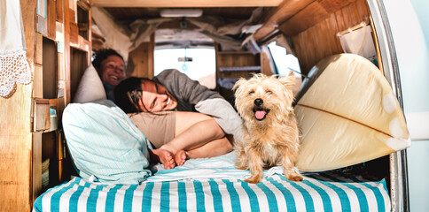 Hipster couple with cute pet traveling together on vintage rv campervan - Wanderlust and life inspiration concept with hippie lovers on mini van adventure trip - Bright warm filter with focus on dog - 480998364
