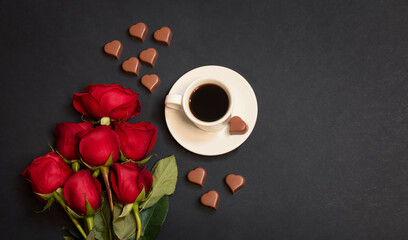 Red roses, cup of coffee and heart shape chocolate candies.