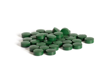Spirulina green pills isolated on a white background close up. Chlorella tablets. Superfood and food supplement.