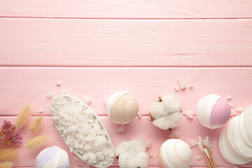 Aroma bath bombs in spa composition with dry flowers and salt on pink wooden background.