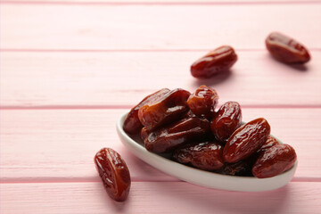 White bowl of dried dates on pink background.