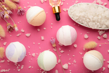Aroma bath bombs in spa composition with dry flowers and salt on pink background.
