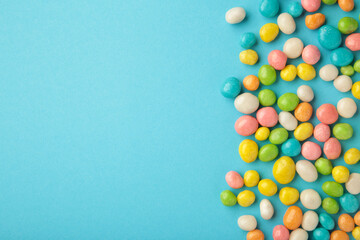 Colorful chocolate candy pills withs space on blue background.